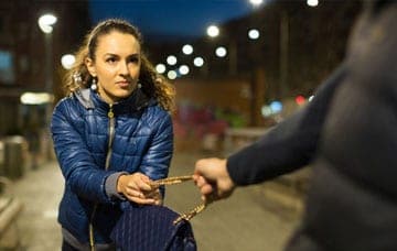 A man robbing woman's bag on the street in the night